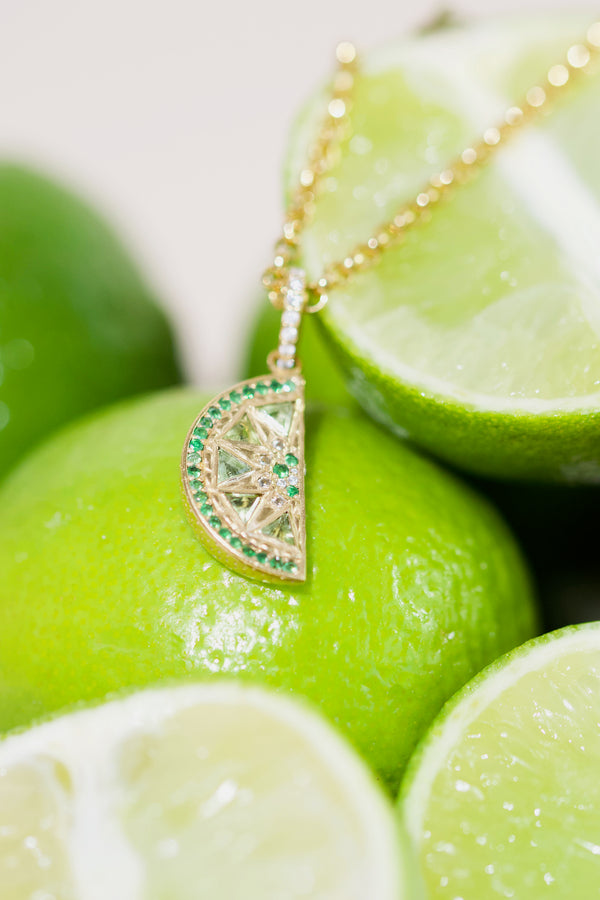 Necklace with a lime-slice gemstone pendant on a background of limes